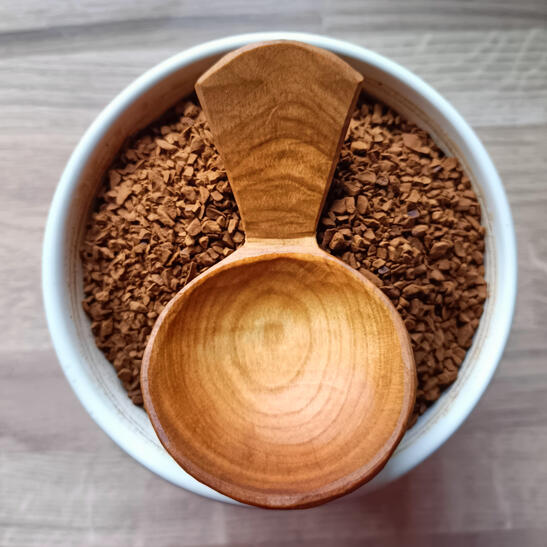 a small cranked cherry scoop sits on top of a jar of coffee grounds